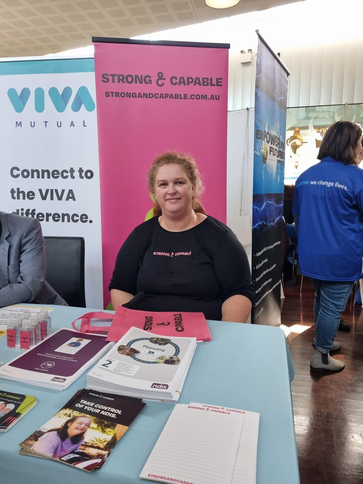 Strong & Capable team member sitting at a table at an Expo
