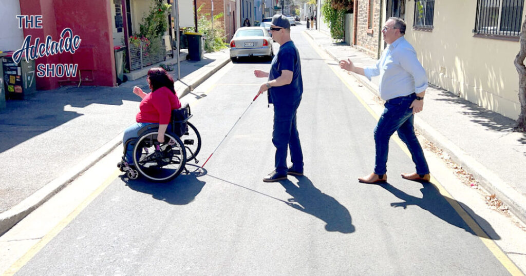 Wheelchair user, man with cane and man walking across a road