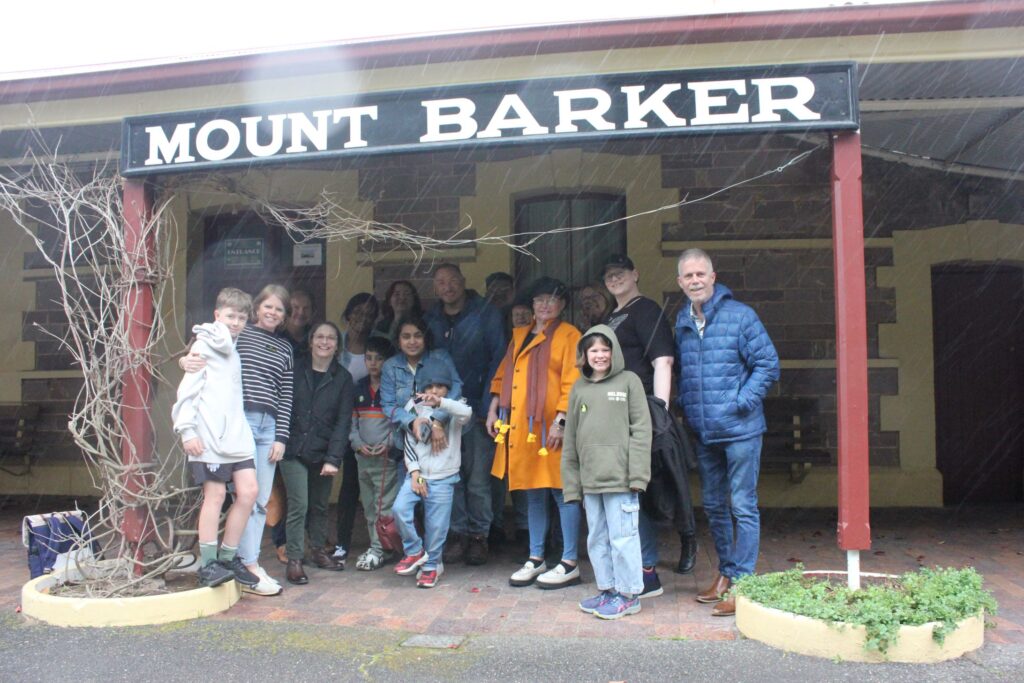 Group of people under a sign that says Mount Barker